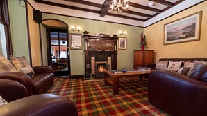 Una sala de estar acogedora con sofás de cuero, chimenea, piso de cuadros y un comedor al fondo.
