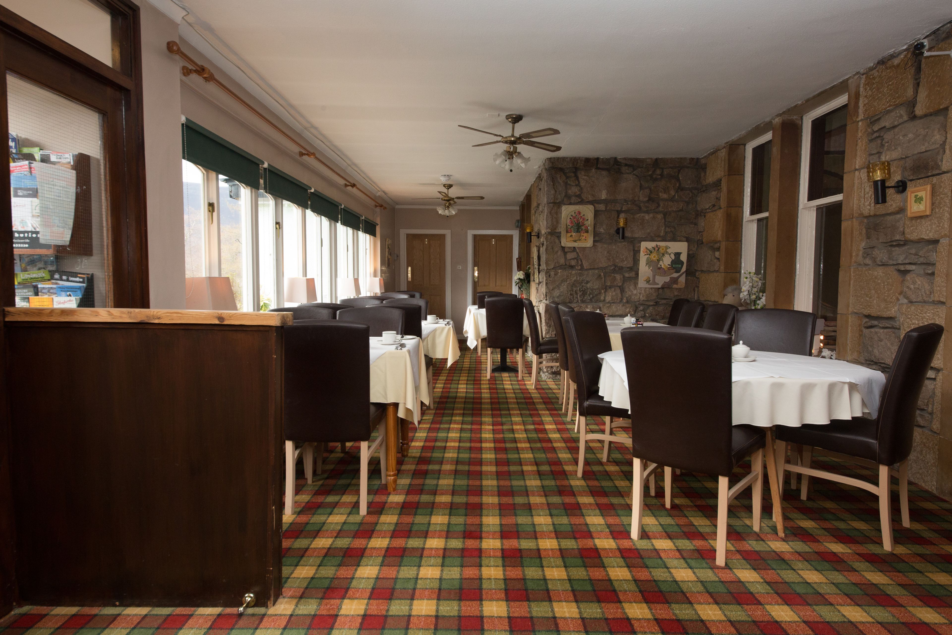 Un restaurante con suelo a cuadros, paredes de madera y varias mesas con sillas.
