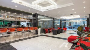 Eine moderne Lobby mit Barbereich, Sitzgelegenheiten und einer Glaswand mit Blick auf die Straße.