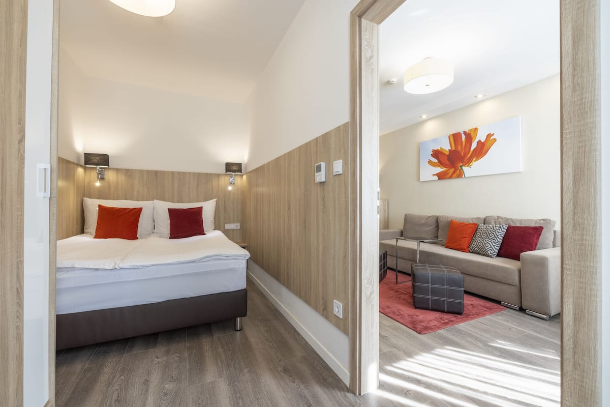 A modern hotel room with a bed, a sofa, and a red rug.