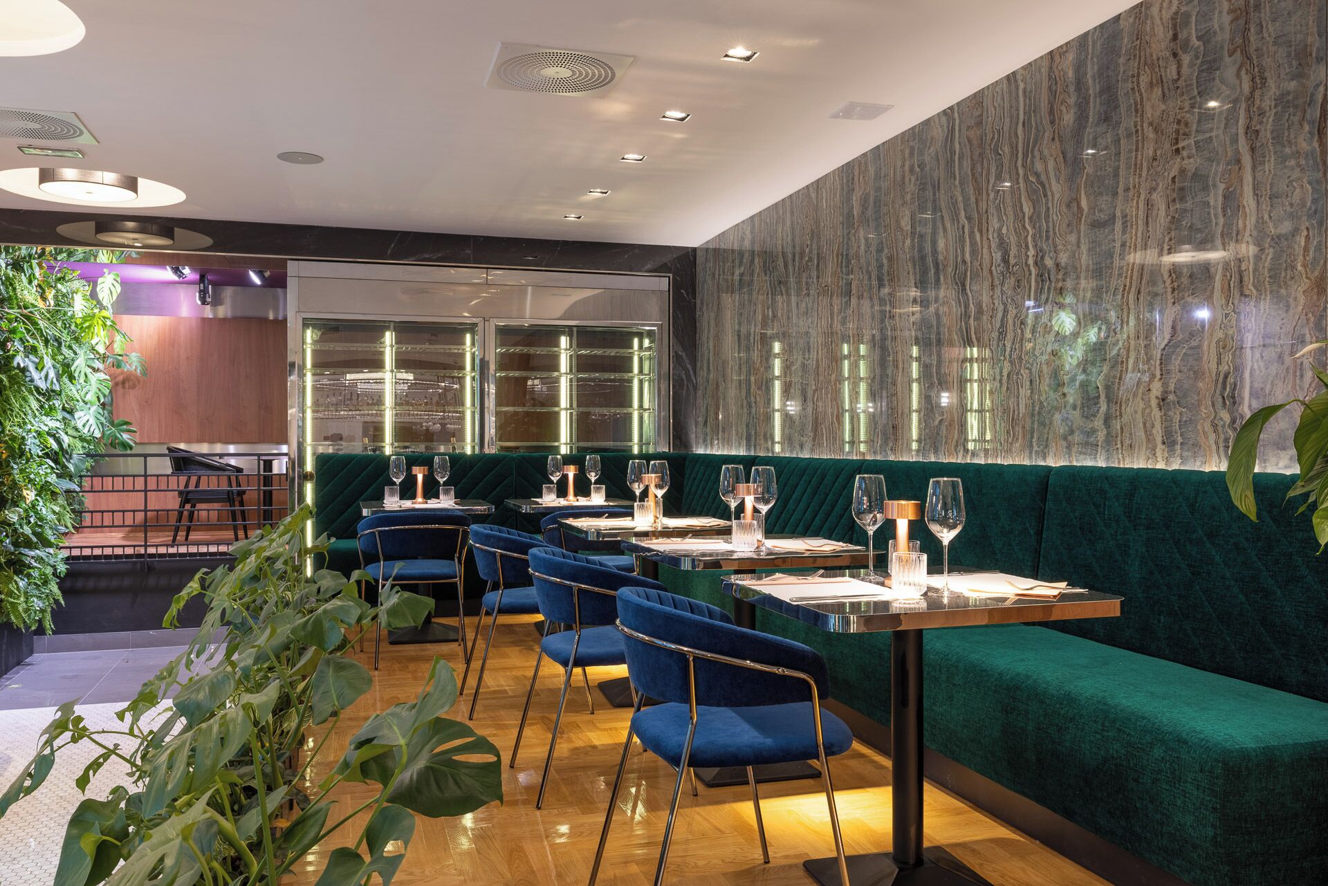 A restaurant with green upholstered booths, wooden tables, and blue chairs.