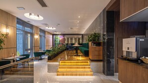 Eine moderne Hotelhalle mit einer zentralen Treppe, Sitzbereichen und einer Rezeption.