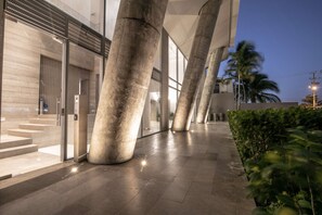 A modern building with large concrete pillars, a glass entrance, and a paved walkway. - Charming studio in Bocagrande (Cartagena)