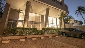 A modern building with large columns, a car parked in front, and palm trees in the background. - Charming studio in Bocagrande (Cartagena)