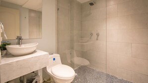 A modern bathroom with a large mirror, a sink, a toilet, and a shower. - Charming studio in Bocagrande (Cartagena)