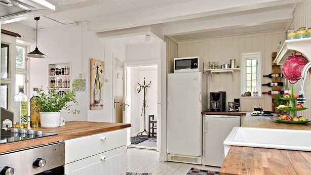 A kitchen with white cabinets, a wooden countertop, a microwave, and a refrigerator. There is a plant on the countertop and a rug on the floor. - Österlen, fantastic cozy guesthouse for Villa Veranda (Ystad M)