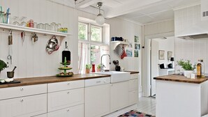 A kitchen with white cabinets, a wooden countertop, and various kitchen utensils and plants. - Österlen, fantastic cozy guesthouse for Villa Veranda (Ystad M)