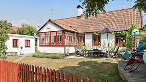 A house with a red-tiled roof, a white exterior, and a wooden deck with outdoor furniture. - Österlen, fantastic cozy guesthouse for Villa Veranda (Ystad M)