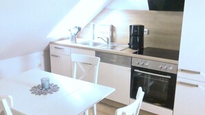 Een kleine keuken met een vaatwasser, fornuis en koffiezetapparaat.