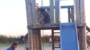Een houten speelconstructie met een glijbaan en een schommel.