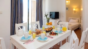 Una mesa con sillas y un televisor al fondo, dispuesta para el desayuno.