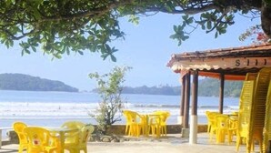 Angolo relax in spiaggia con sedie e tavoli di plastica gialla, con vista sull'oceano.