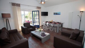 A modern living room with a sofa, a coffee table, and a dining area with a table and chairs.