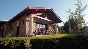 A building with a red roof, large windows, and a patio area with chairs.