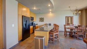 Una cocina moderna con una isla central, armarios de madera y una zona de comedor con candelabro.
