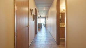 Un pasillo con puertas de madera, suelo de baldosas y ventilador de techo.