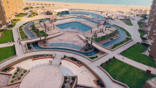 Un resort con varias piscinas, una playa y vistas al océano.