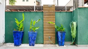 A green wall with three blue planters containing plants, a wooden fence, and a hose. - At Casa em Ubatuba - Praia do Itaguá, excellent for families and long stays. (Ubatuba)