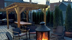 Un patio al aire libre con una pérgola, asientos y una chimenea.