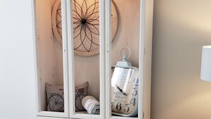 Un mueble blanco con detalles decorativos y un reloj, situado en una habitación con un sofá gris y una alfombra mullida.