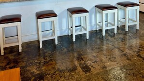 Una cocina con pared de ladrillo, un reloj grande, luces colgantes y taburetes de bar.