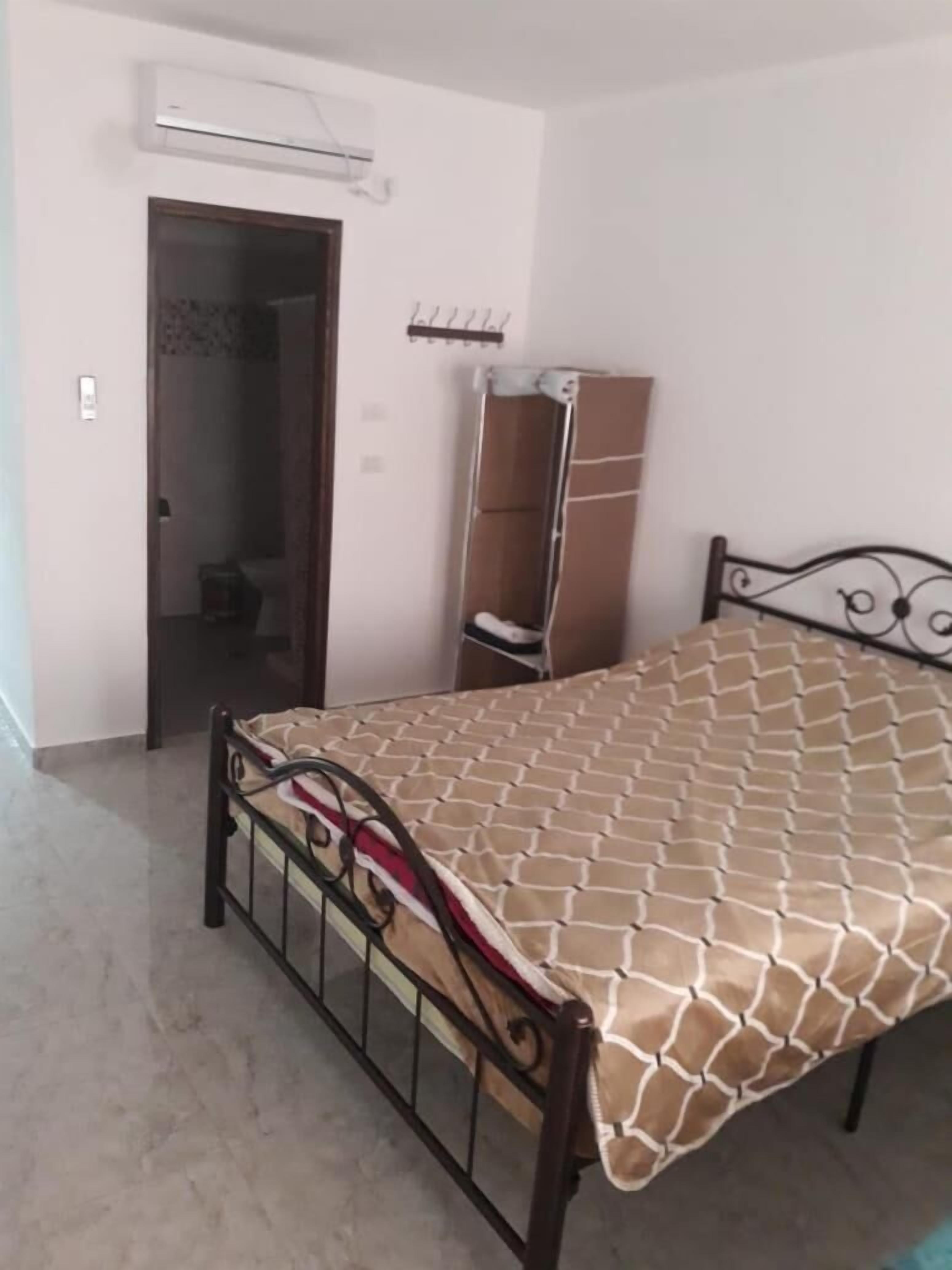 A bedroom with a bed, a wardrobe, and an air conditioning unit.