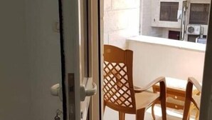 A view through a glass door into a balcony area with a wooden chair and a table. - Chez William (Bethlehem)