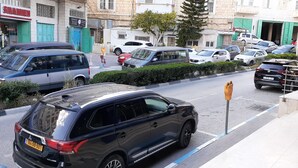 A street view with parked cars, a visible storefront with a sign, and a pedestrian crossing. - Chez William (Bethlehem)
