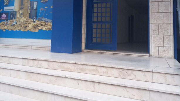 A building entrance with a blue door and a large advertisement on the wall. - Chez William (Bethlehem)