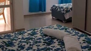 A bedroom with a bed, a window with blue curtains, a wardrobe, and a door leading to a balcony. - Chez William (Bethlehem)