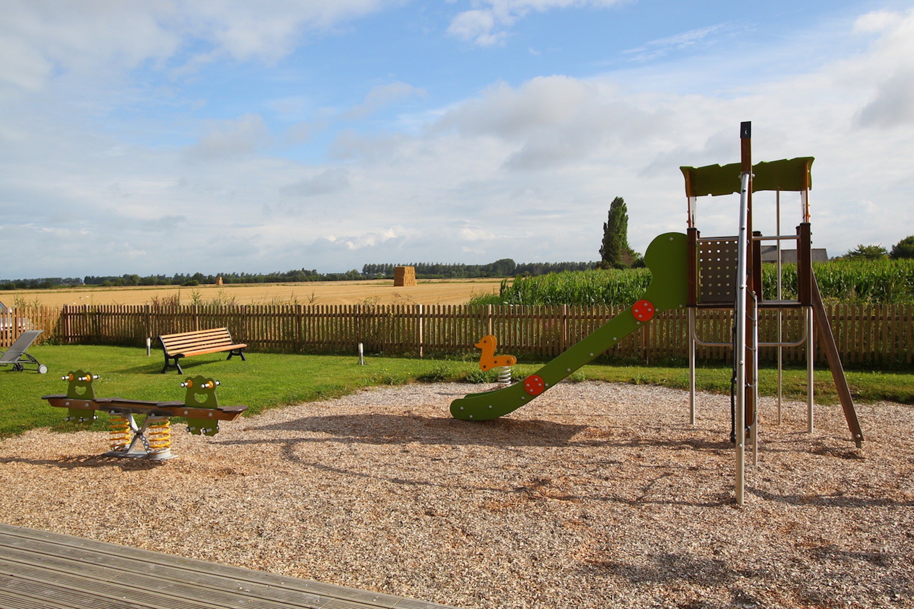 A playground with a seesaw, a climbing structure, and a bench.