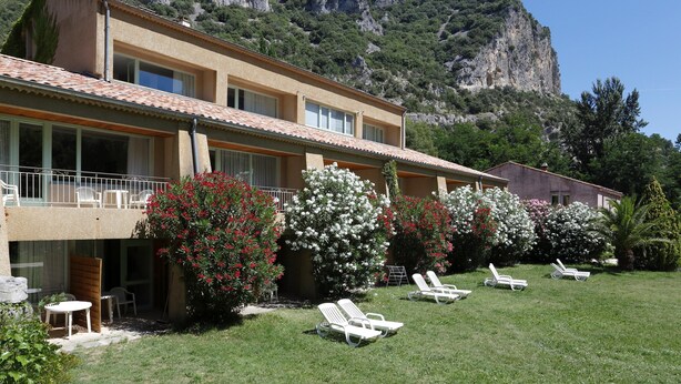 A hotel with a terrace, white lounge chairs, and a mountain backdrop. - Superbe STU Vue sur la Rivière Ardèche (VALLON-PONT-D’ARC)