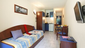 A compact room with a bed, a small kitchenette, a dining area, and a TV. - Superbe STU Vue sur la Rivière Ardèche (VALLON-PONT-D’ARC)
