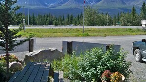 A scenic view of a mountain range with a flag, a road, and a parked vehicle.