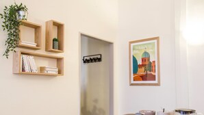 A modern room with a minimalist design, featuring a wooden bookshelf, a framed artwork of Toulouse, and a table with a teapot and cups. - Le Saint Nicolas - One Bedroom Apartment, Sleeps 4 (Toulouse)