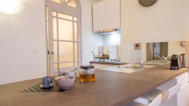 A modern kitchen with a large window, a clock, and a sink. - Le Saint Nicolas - One Bedroom Apartment, Sleeps 4 (Toulouse)