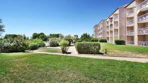 Un hôtel à plusieurs étages doté de balcons, d’une pelouse bien entretenue et offrant une vue sur un ciel dégagé.