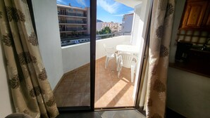 A balcony with a table and chairs, a sliding glass door, and a view of neighboring buildings. - Summerland 3 (Los Cristianos)