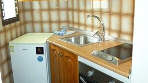 A compact kitchen with wooden cabinets, a built-in sink, a refrigerator, and an oven. - Summerland 3 (Los Cristianos)