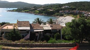 Un hotel costero con varias edificaciones, una playa y vistas al mar.