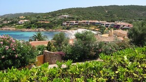 Un complejo turístico en la costa con varias edificaciones, una playa y abundante vegetación.