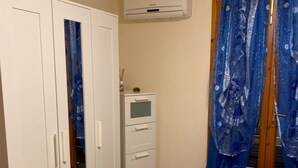 A bedroom with a bed, a wardrobe, a small cabinet, and a window with blue curtains. - semi-detached house n residential area (Quartu Sant'Elena)
