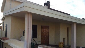 A two-story building with a balcony, a wooden door, and a small trash bin. - semi-detached house n residential area (Quartu Sant'Elena)