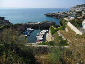 Un puerto costero con barcos amarrados, acantilados rocosos y un muro de piedra.