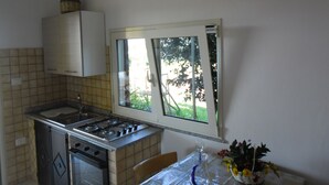 A kitchen with a gas stove, oven, and a window overlooking greenery.