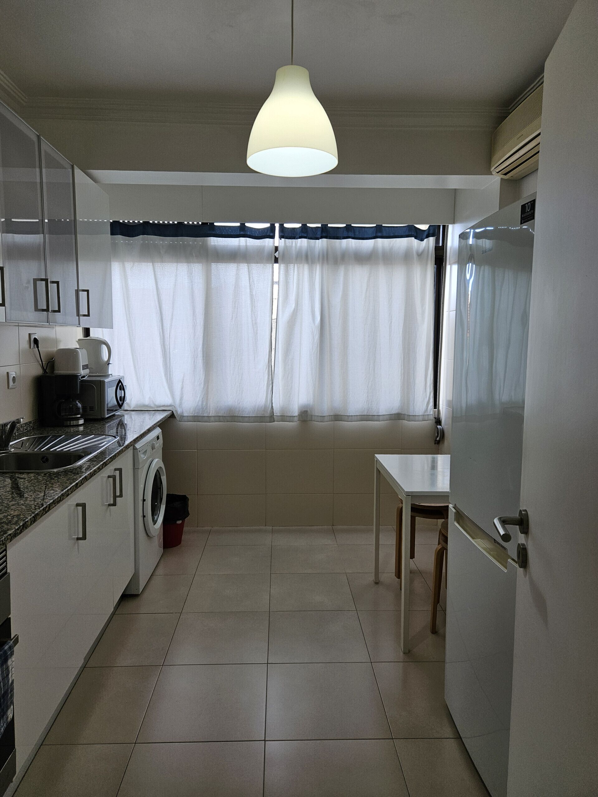 A compact kitchen with a washing machine, a coffee maker, and a table.