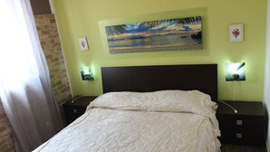 A bedroom with a large bed, a nightstand with a lamp, and a painting on the wall.