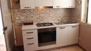 A compact kitchen with white cabinets, a gas stove, an oven, and a sink.