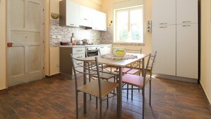 A compact kitchen with white cabinets, a dining table with chairs, and a window providing natural light.