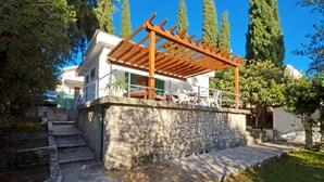 Una escalera de piedra que conduce a un edificio blanco con una pérgola de madera.